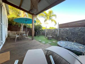 a patio with a table and chairs and an umbrella at Ti Kaz avec SPA, proche du lagon in Saint-Gilles les Bains