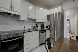 uma cozinha com armários brancos e uma mesa de madeira em The NDG Nest A Relaxing 3BR Getaway in DT MTL em Montréal