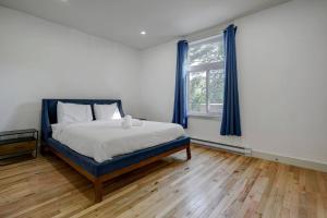 um quarto com uma cama e uma janela com cortinas azuis em The NDG Nest A Relaxing 3BR Getaway in DT MTL em Montréal mais 2 fotografias