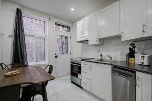 uma cozinha com armários brancos e uma mesa dentro em The NDG Nest A Relaxing 3BR Getaway in DT MTL em Montréal