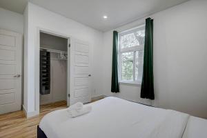 um quarto com uma cama branca e uma janela em The NDG Nest A Relaxing 3BR Getaway in DT MTL em Montréal