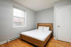 Un dormitorio con una cama con sábanas blancas y una ventana. en Stylish 2BR in Montreal, en Montreal