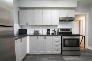 Una cocina con gabinetes blancos y un horno de estufa. en Stylish 2BR in Montreal, en Montreal