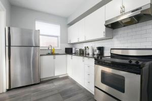 Una cocina con gabinetes blancos y un refrigerador de acero inoxidable. en Lovely 2BR on Walkley, en Montreal