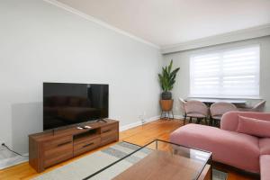 a living room with a pink couch and a flat screen tv at Beautiful 2BR on Walkley in Montréal