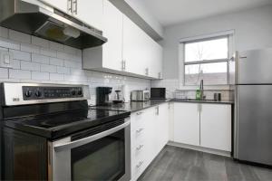 una cocina con armarios blancos y un aparato de acero inoxidable en Amazing 2BR on Walkley, en Montreal 9 fotos más