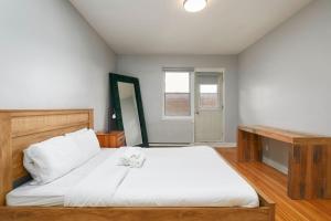 Un dormitorio con una gran cama blanca y una ventana. en Amazing 2BR on Walkley, en Montreal