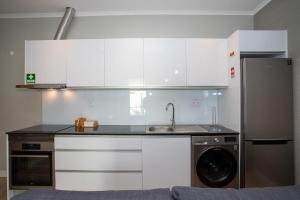 a kitchen with white cabinets and a sink and a dishwasher at Casa do Gaveto in Água de Pau