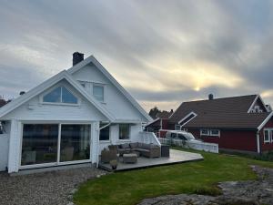 a white house with a patio with a couch at Sommerferie i skjærgårdsidyll på Langenes i Kristiansand in Kristiansand