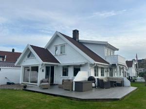 a white house with a deck in the yard at Sommerferie i skjærgårdsidyll på Langenes i Kristiansand in Kristiansand +12 photos