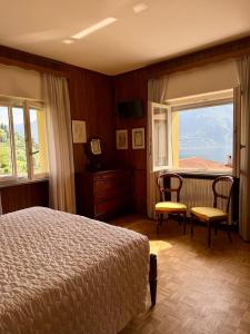 a bedroom with a bed and two chairs and a window at Ersilia ed Ennio Apartment in Bellagio