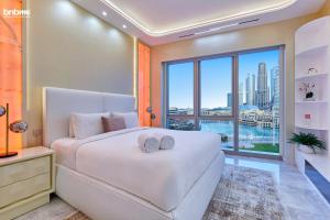 a bedroom with a large white bed and a large window at bnbme - Luxury Downtown Dubai Apt Burj Khalifa Fountain Views Pool Gym Parking in Dubai