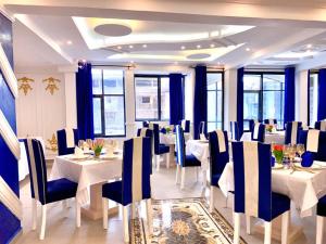 a dining room with white tables and blue chairs at Guiko Palace Hôtel in Douala