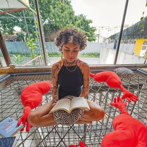una mujer sentada en una silla leyendo un libro en Don Hostel, en Villavicencio