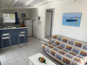 a room with a bed and a kitchen and a table at LE LAGON BLEU, BUNGALOWS Vue sur MER , 350 m de la plage in Sainte-Anne +24 photos
