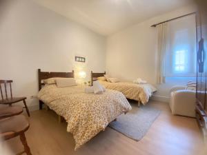 Un dormitorio con dos camas y una ventana. en APARTAMENTOS TURÍSTICOS WAMBALORE, en Pampliega