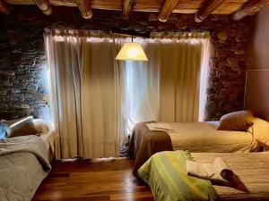 a bedroom with two beds and a window with curtains at Refugio Del Pintor in Tilcara