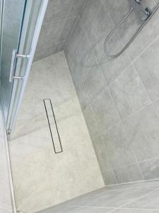 a shower with a glass door and a tile floor at Tudor Close NW9 8SU in London