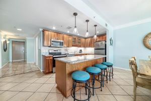 a kitchen with wooden cabinets and blue stools at Phoenix X Unit 803 in Orange Beach
