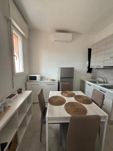 a white kitchen with a table and chairs in it at A due passi dal mare - OpenSpace in Porto Garibaldi