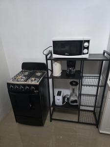 a kitchen with a stove and a microwave on a shelf at Sunset 22 by the Airport Apt#6 in Montego Bay