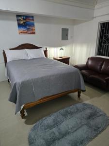 a bedroom with a large bed and a couch at Sunset 22 by the Airport Apt#6 in Montego Bay