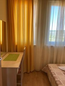 a bedroom with a desk and a window and a bed at Harmony Hills Tomovi Apartment H41 in Rogachevo +4 photos