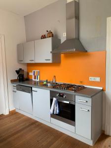 a kitchen with a stove and an orange wall at Ferienwohnung Tichelmeister 45261 in Ditzum