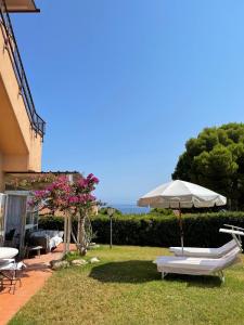 a patio with chairs and an umbrella and the ocean at Loggia di Capo d'Arco - Goelba in Capo D'Arco