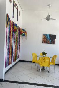 a dining room with yellow chairs and a table at Pousada Recife Tropical in Recife