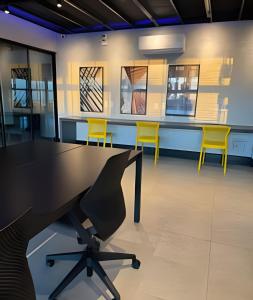 a conference room with a table and yellow chairs at Studio Concept Avenida das Esmeraldas in Marília