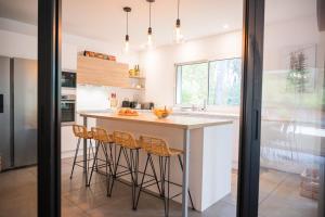 a kitchen with a island with bar stools at Connemara, Superbe Villa avec piscine, au cœur de la forêt, accès à la plage en vélo in Soorts-Hossegor