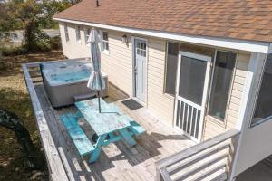 una terraza con bañera de hidromasaje y sombrilla en Hot Tub Walk to Beach and Dog Friendly, en Kill Devil Hills