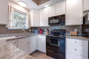 cocina con armarios blancos y fogones negros en Hot Tub Walk to Beach and Dog Friendly, en Kill Devil Hills