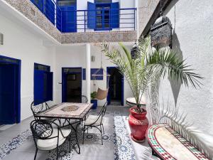 un patio con mesa, sillas y una maceta en Riad de jeanne, en Essaouira