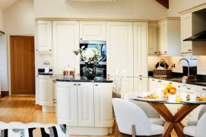 eine Küche mit weißen Schränken und einem Tisch mit Obst darauf in der Unterkunft Hillock's Farm Cottage, Luxury in Moorsholm