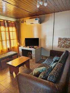 a living room with a couch and a tv at Cabañas Las Dunas in El Nihuil