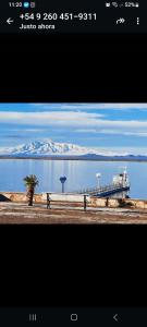 a picture of a pier with snow capped mountains in the background at Cabañas Las Dunas in El Nihuil