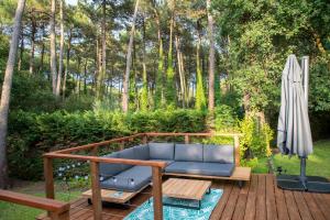 a blue couch on a deck with an umbrella at Connemara, Superbe Villa avec piscine, au cœur de la forêt, accès à la plage en vélo in Soorts-Hossegor
