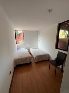 a bedroom with two beds and a chair in it at Hostería Vitacura in Santiago