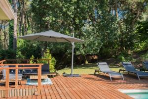 a patio with a table and an umbrella and chairs at Connemara, Superbe Villa avec piscine, au cœur de la forêt, accès à la plage en vélo in Soorts-Hossegor