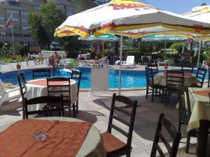 a restaurant with tables and umbrellas next to a pool at Blue sky apartments in Sunny Beach