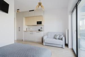 a bedroom with a bed and a chair and a kitchen at S1 Apartamenty Rewa in Rewa