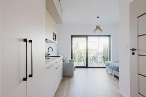 a kitchen with white cabinets and a living room at S1 Apartamenty Rewa in Rewa