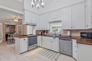a large white kitchen with white cabinets and a table at Downtown Cottage in Lake Charles