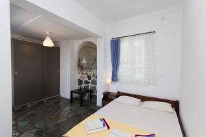 a bedroom with a white bed and a window at PAROS APARTMENT MELAS α1 in Parikia