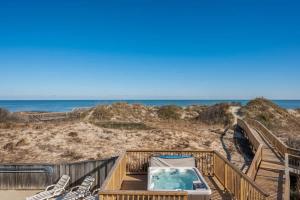 a hot tub on a deck next to the beach at Beachfront Bliss with Pool & Hot Tub in Corolla