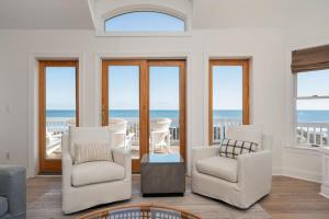 a living room with white chairs and a view of the ocean at Beachfront Bliss with Pool & Hot Tub in Corolla