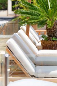 a row of white lounge chairs with a palm tree on top at La Garoupe-Gardiole in Antibes