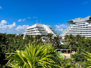 坎昆Luna, 2 Beds en la mejor ubicación de Cancún的两栋白色大楼，周围有树木和棕榈树